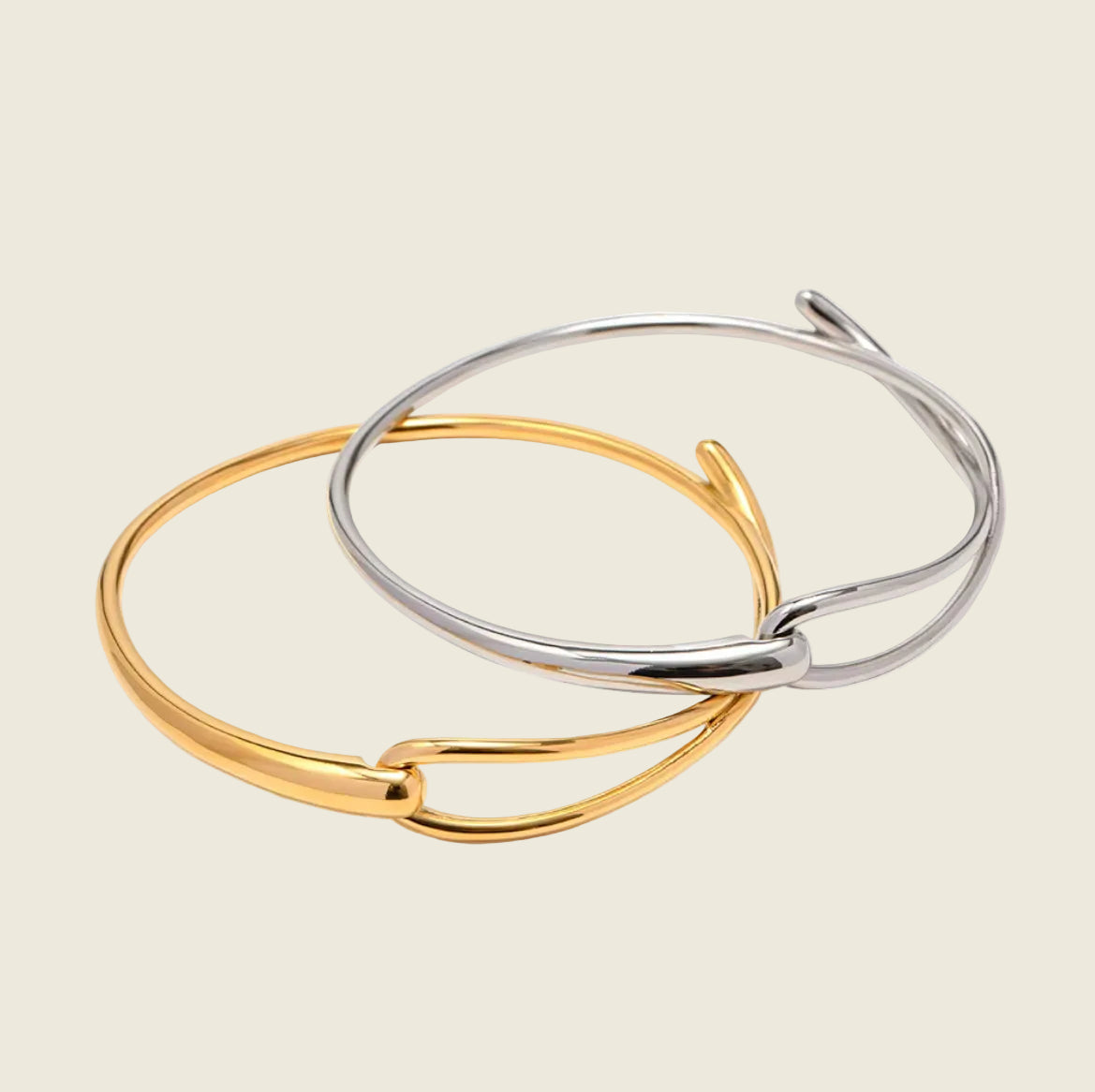 Two minimalist open bangle bracelets, one in polished gold and one in polished silver, overlapping on a clean white background.